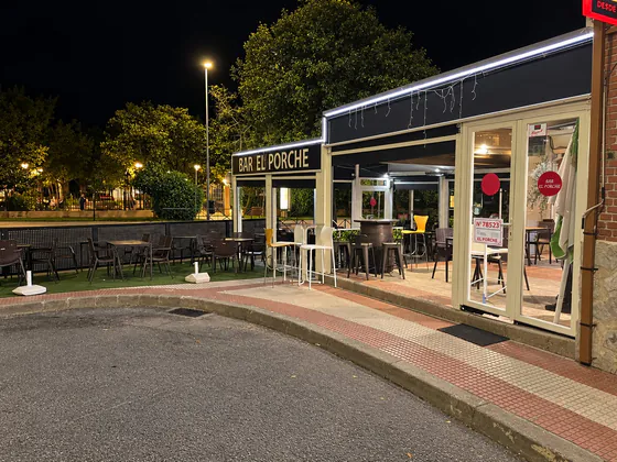 Entrada de Bar El Porche de noche, con el rótulo y la terraza iluminados