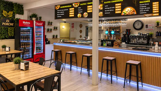 Interior de Bar El Porche: barra de madera con luz LED, neveras de bebidas y paneles con la carta
