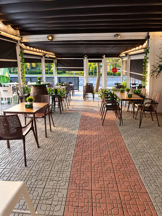 Terraza cubierta de El Porche con mesas de madera y luces cálidas
